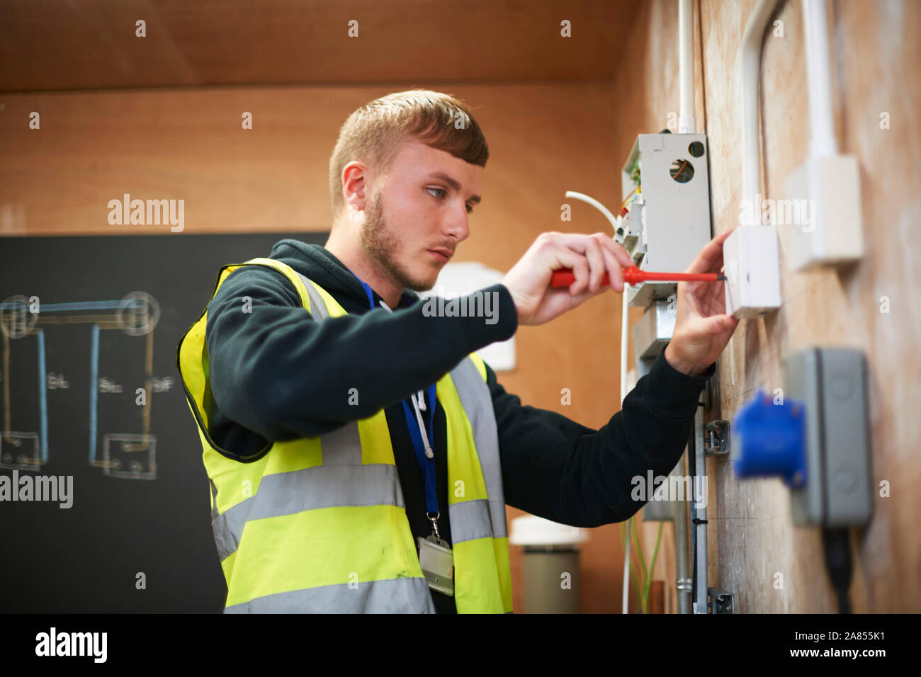 Männliche Elektriker Schüler üben in Werkstatt Stockfoto