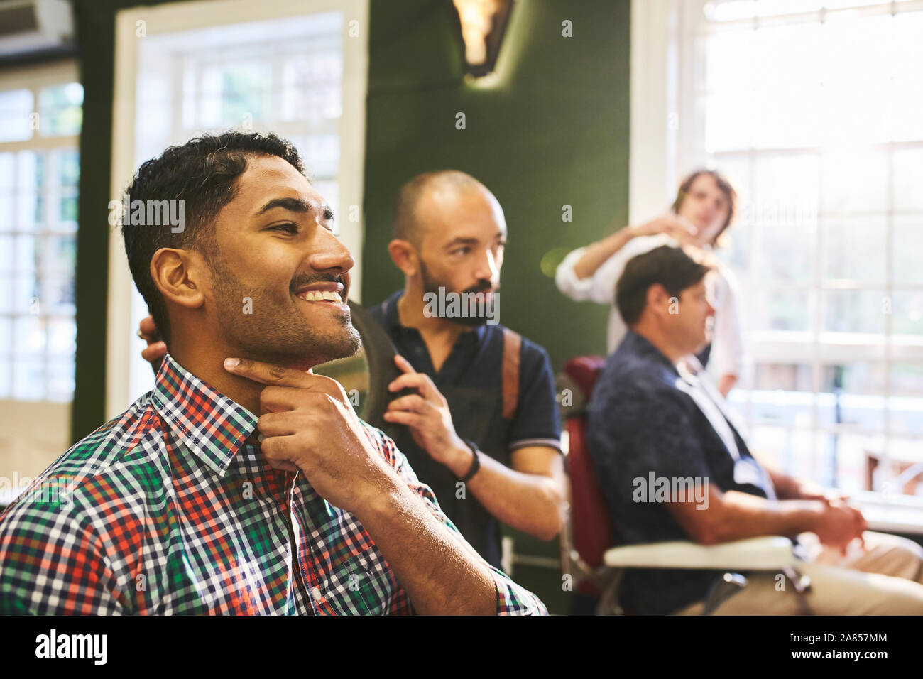 Lächelnd männlichen Kunden Kontrolle rasierten Gesicht in Barbershop Stockfoto