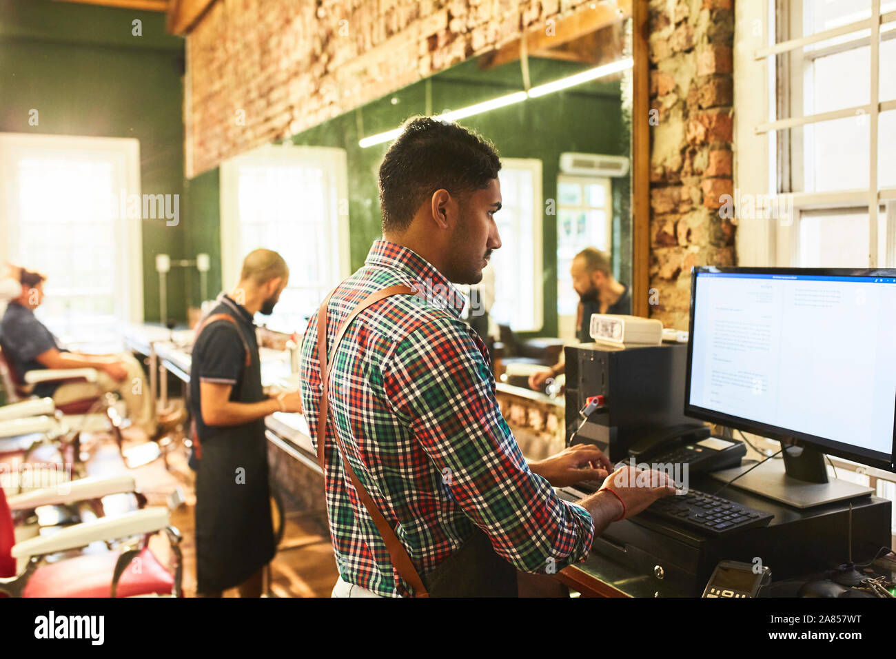 Männliche Friseur mit Computer im barbershop Stockfoto