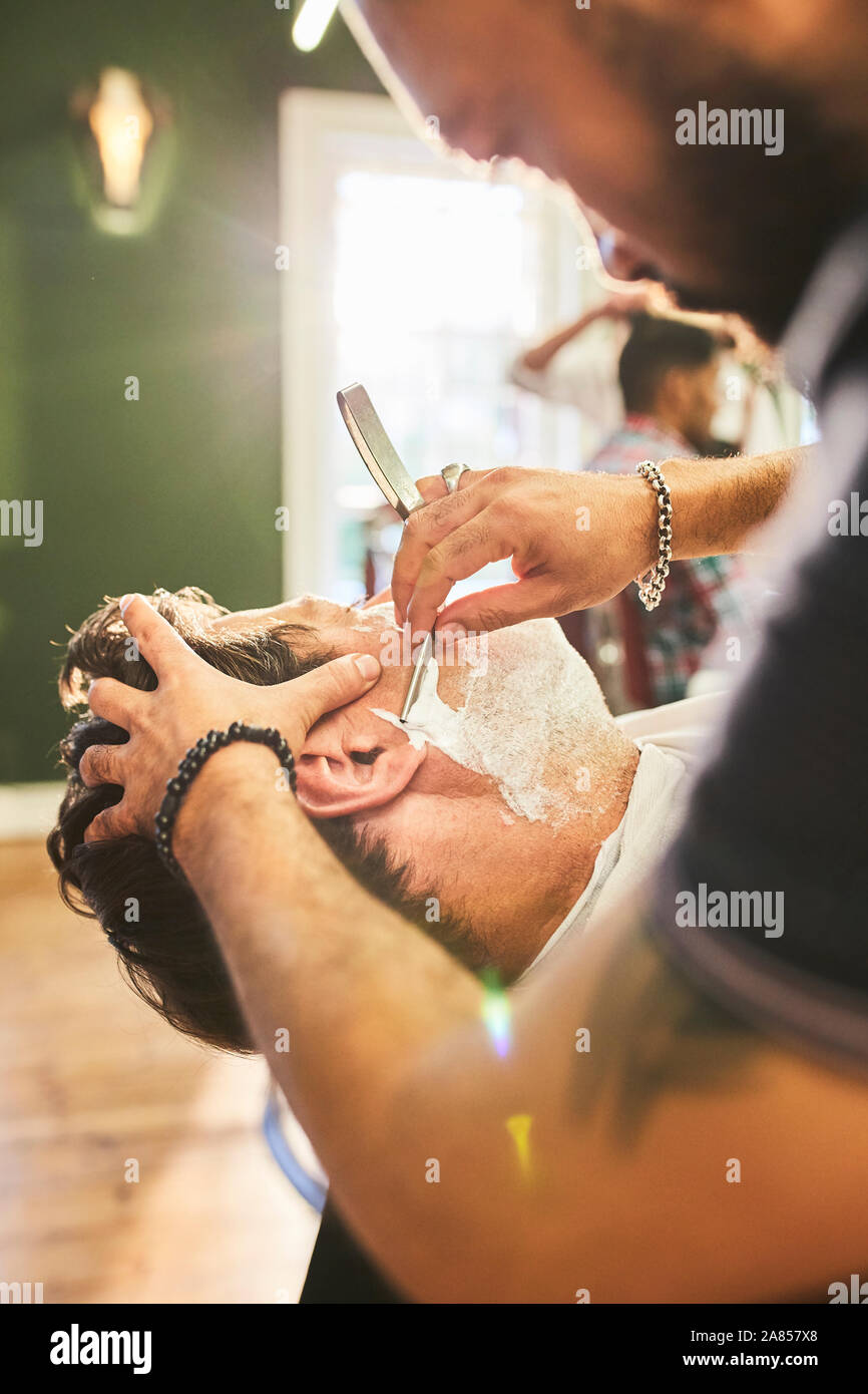 Männliche Friseur eine Rasur in barbershop Kunde Stockfoto