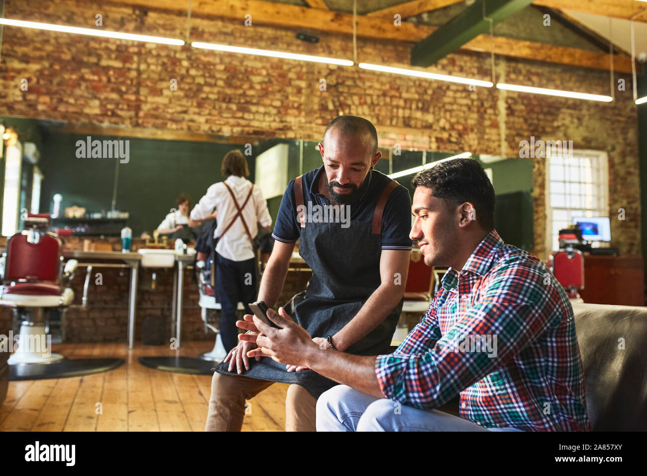 Männliche Friseur- und Kunden mit digitalen Tablette im barbershop Stockfoto