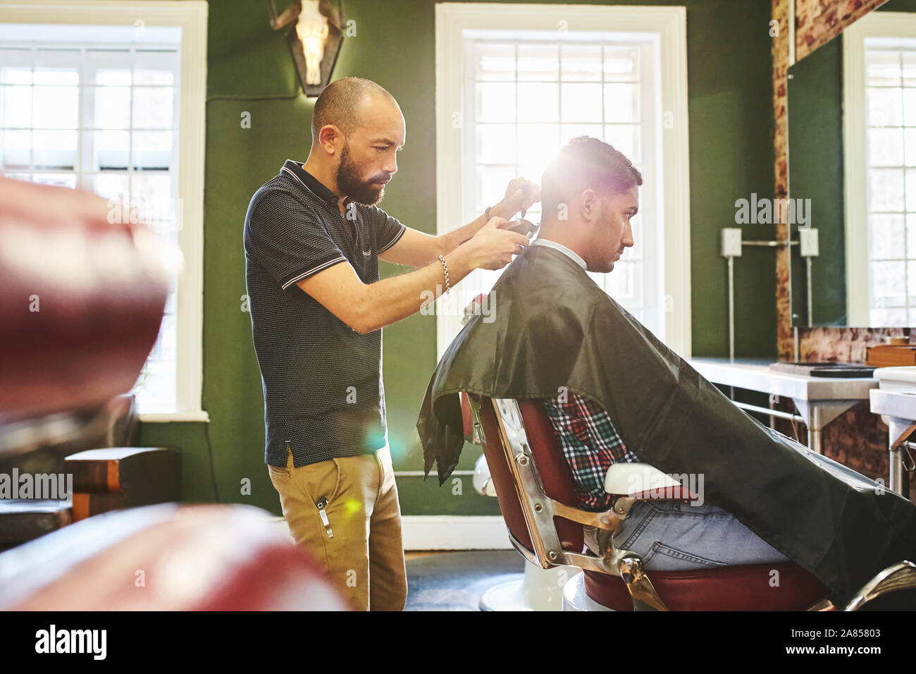 Fokussierte männliche Friseur dem Kunden einen Haarschnitt in Barbershop Stockfoto