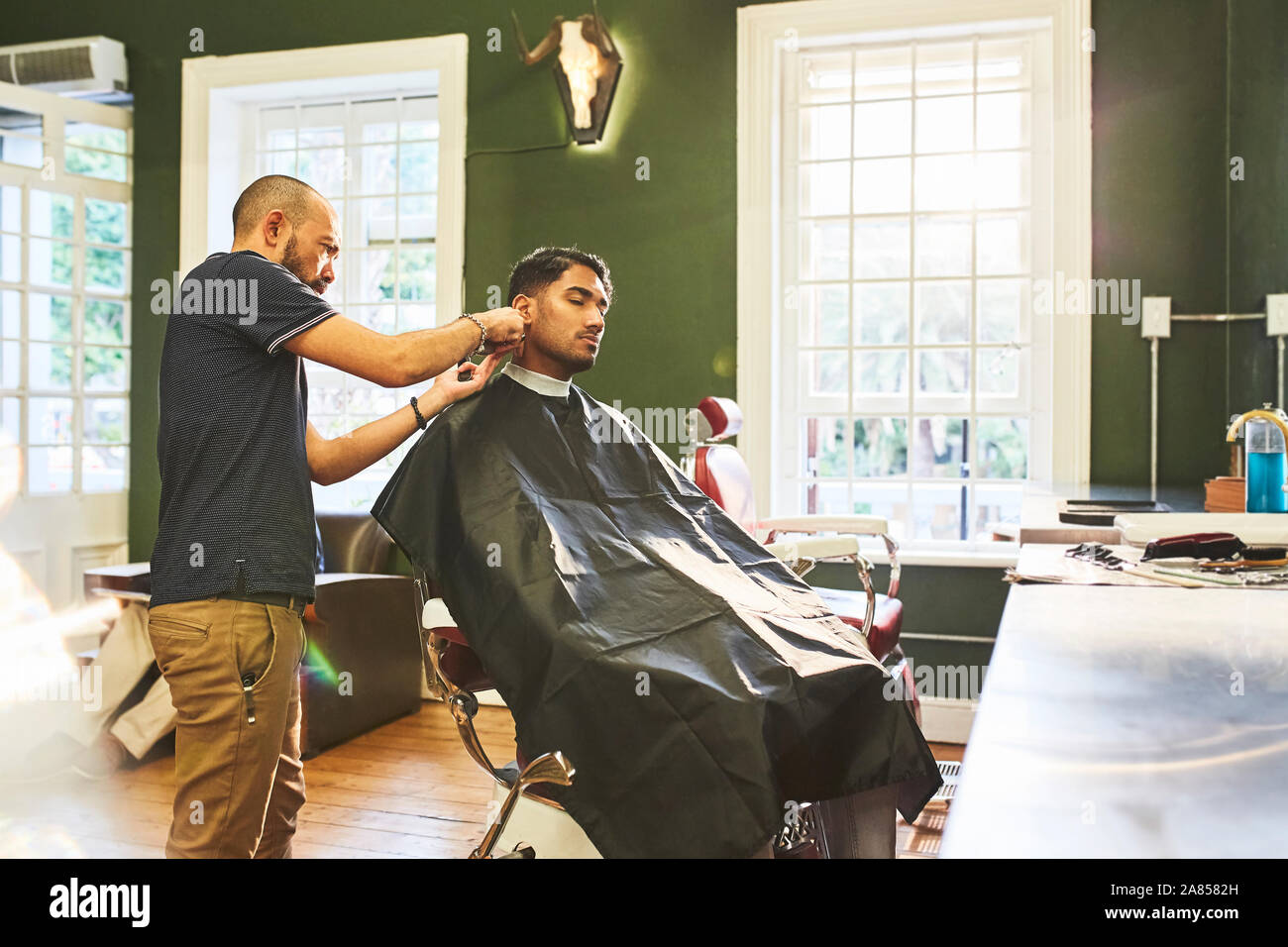 Männliche Friseur dem Kunden einen Haarschnitt in Barbershop Stockfoto