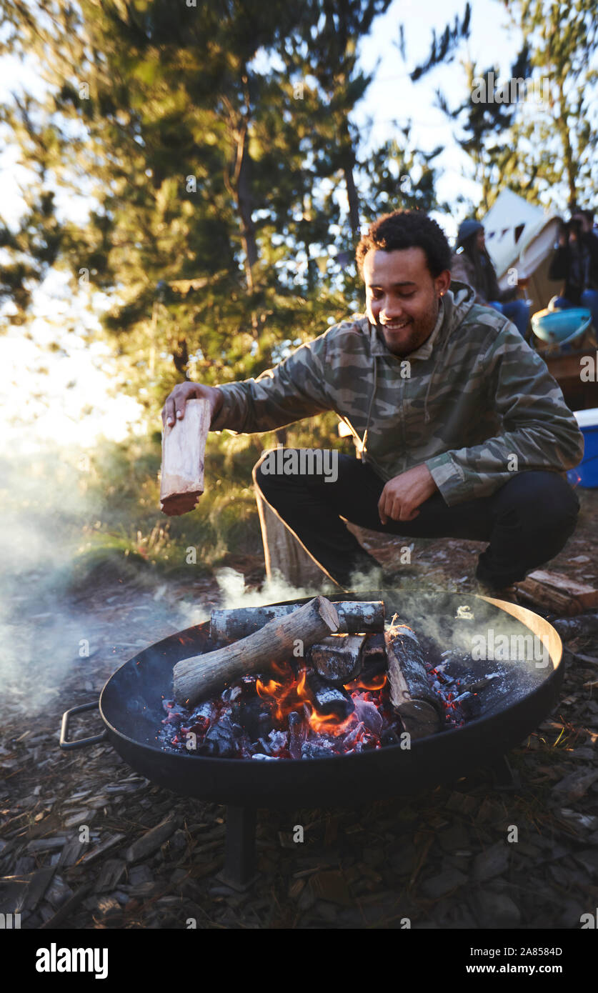 Mann hinzufügen Brennholz Lagerfeuer zu Campingplatz Stockfoto