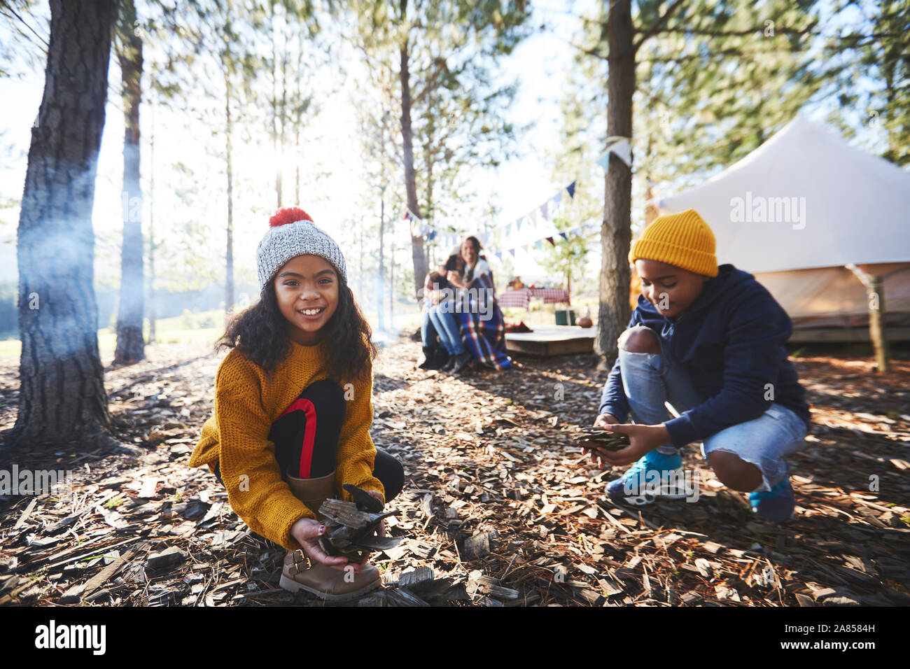 Portrait lächelnde Mädchen sammeln Anzünden bei Sunny Campingplatz in Holz Stockfoto