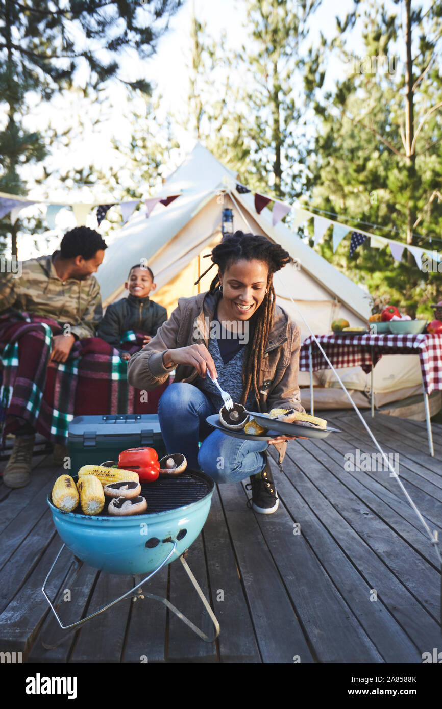 Lächelnde Frau Kochen Gemüse auf Camping Grill Stockfoto