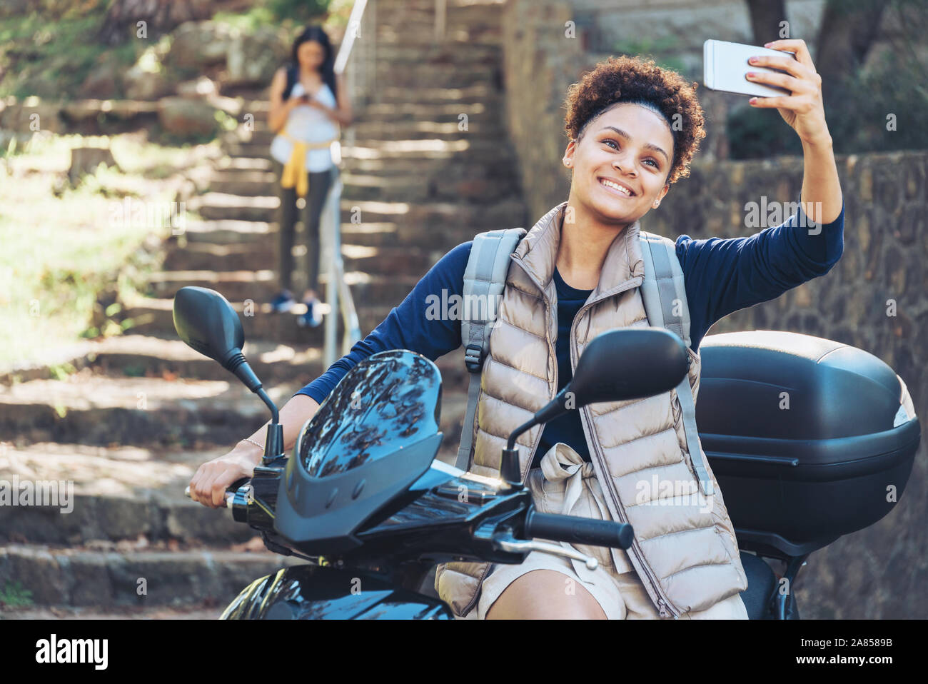 Junge Frau von selfie mit Fotohandy auf Motorroller Stockfoto