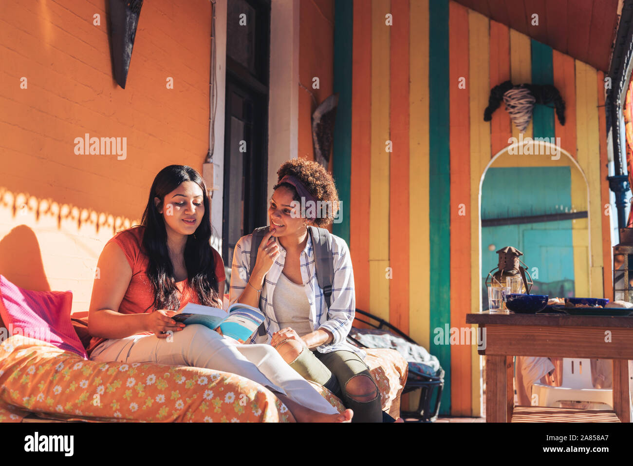 Junge Frauen Freunde lesen Buch über sonnige Terrasse Stockfoto