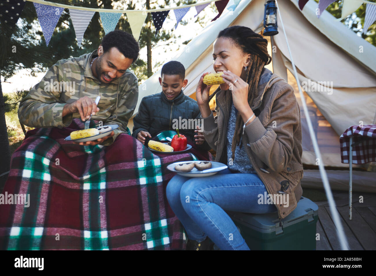 Familie essen Maiskolben auf dem Campingplatz Stockfoto