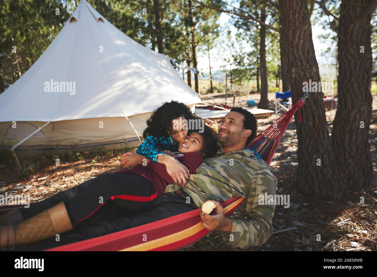 Glückliche, unbeschwerte Familie Relaxen in der Hängematte auf einem Campingplatz im Wald Stockfoto