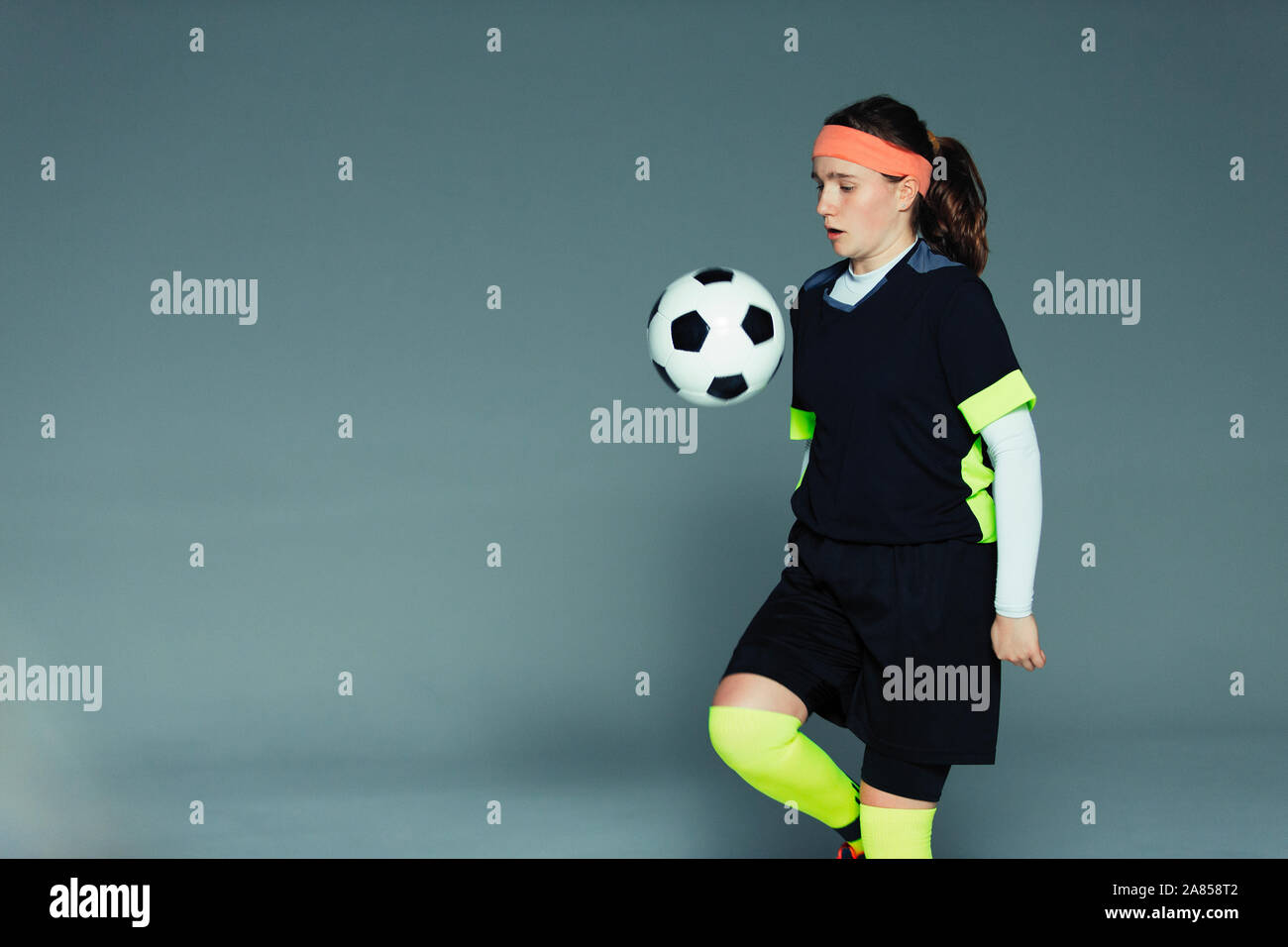 Junges Mädchen Fußball-Spieler springenden Ball auf Knie Stockfoto