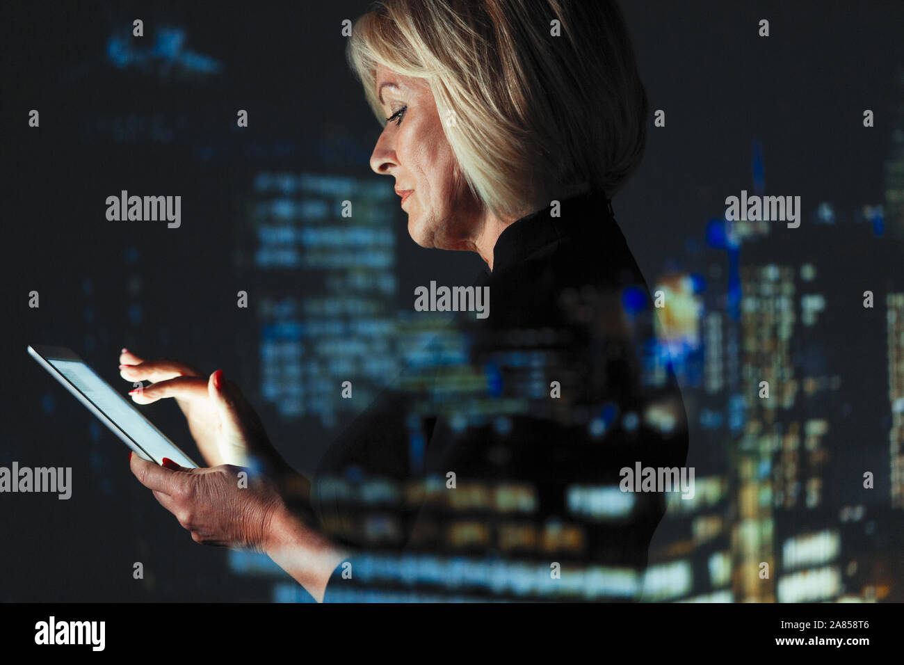 Double Exposure Geschäftsfrau mit digitalen Tablette gegen Hochhaus Lichter in der Nacht Stockfoto