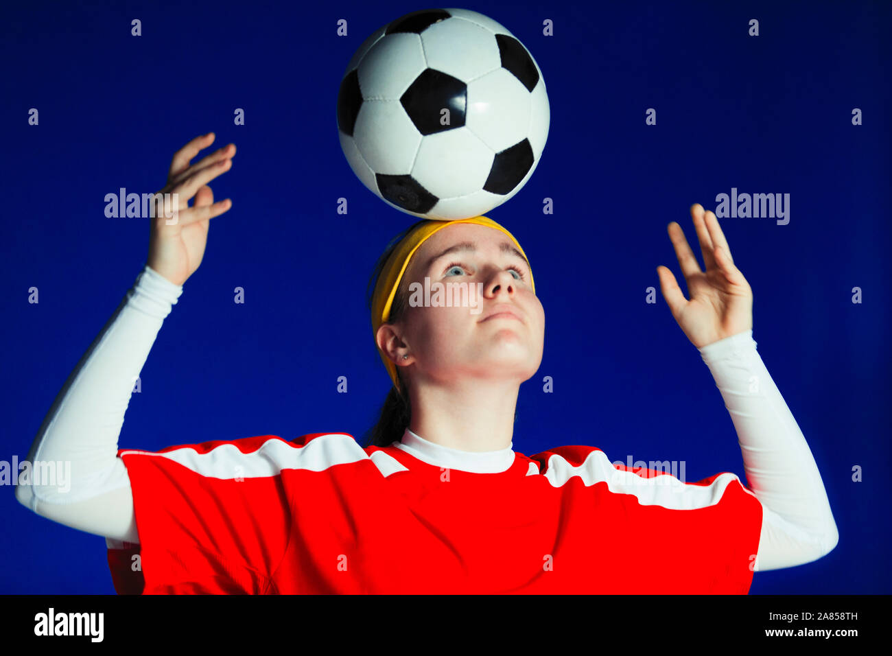 Junges Mädchen Fußball-Spieler balancing Fußball auf den Kopf Stockfoto