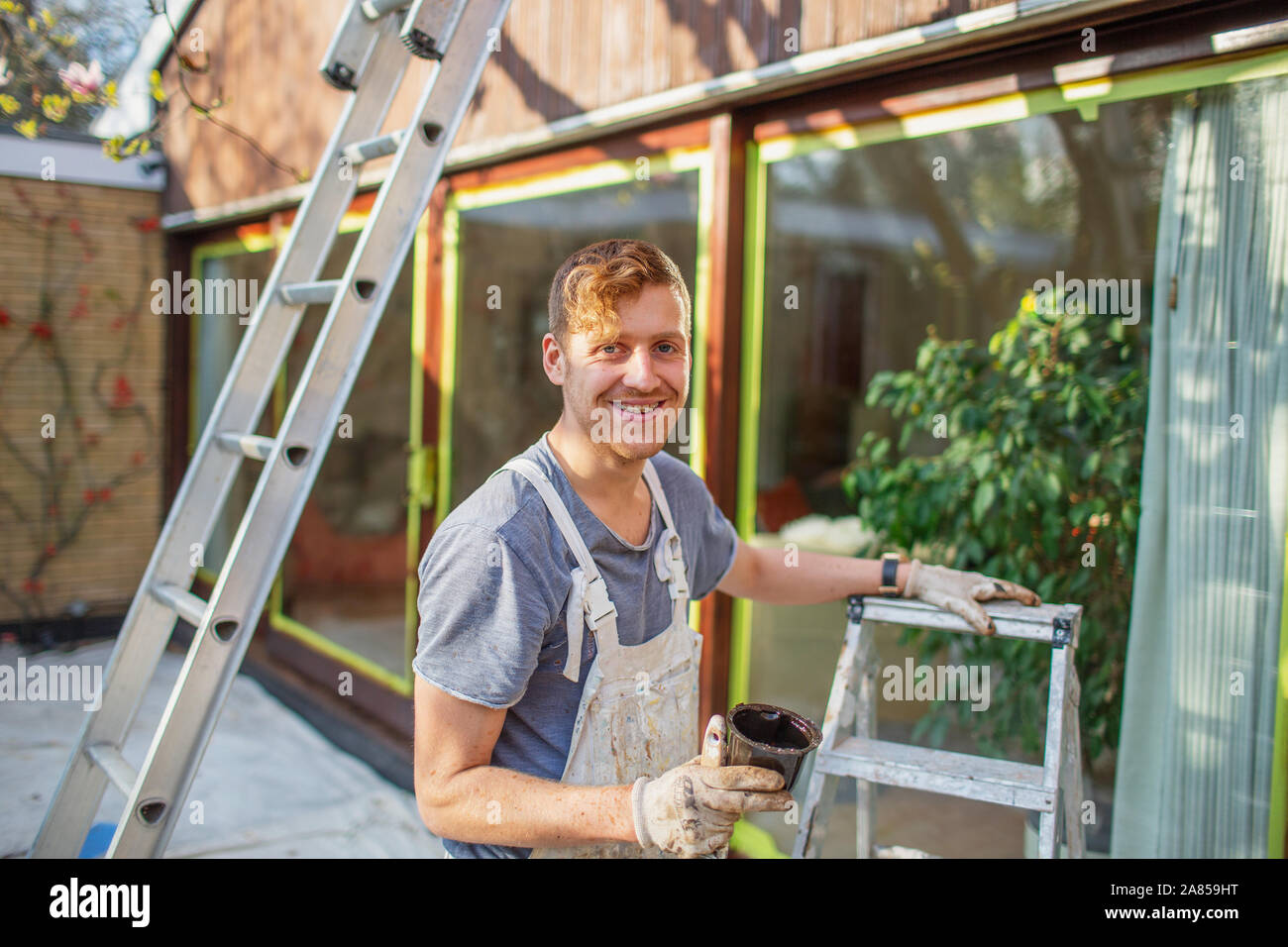 Portrait zuversichtlich männlicher Maler mit Leiter lackieren home Exterieur Stockfoto