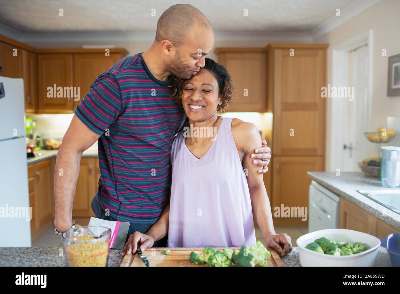 Liebevolle Mann umarmt Frau Kochen in der Küche Stockfoto