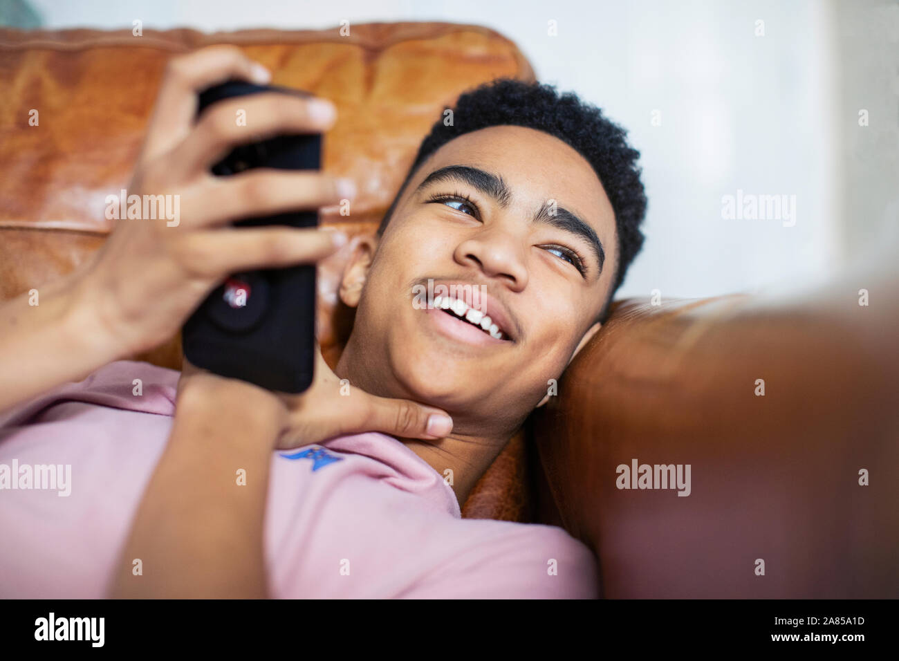 Lächelnd Teenager mit Smart Phone auf dem Sofa Stockfoto
