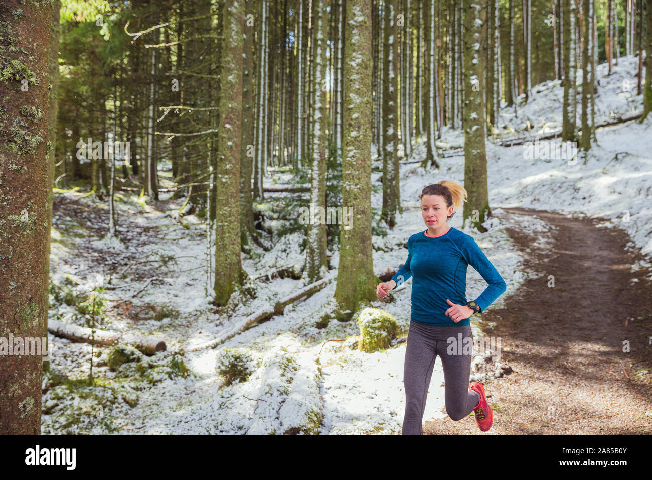 Frau joggen auf Trail im verschneiten Wald Stockfoto