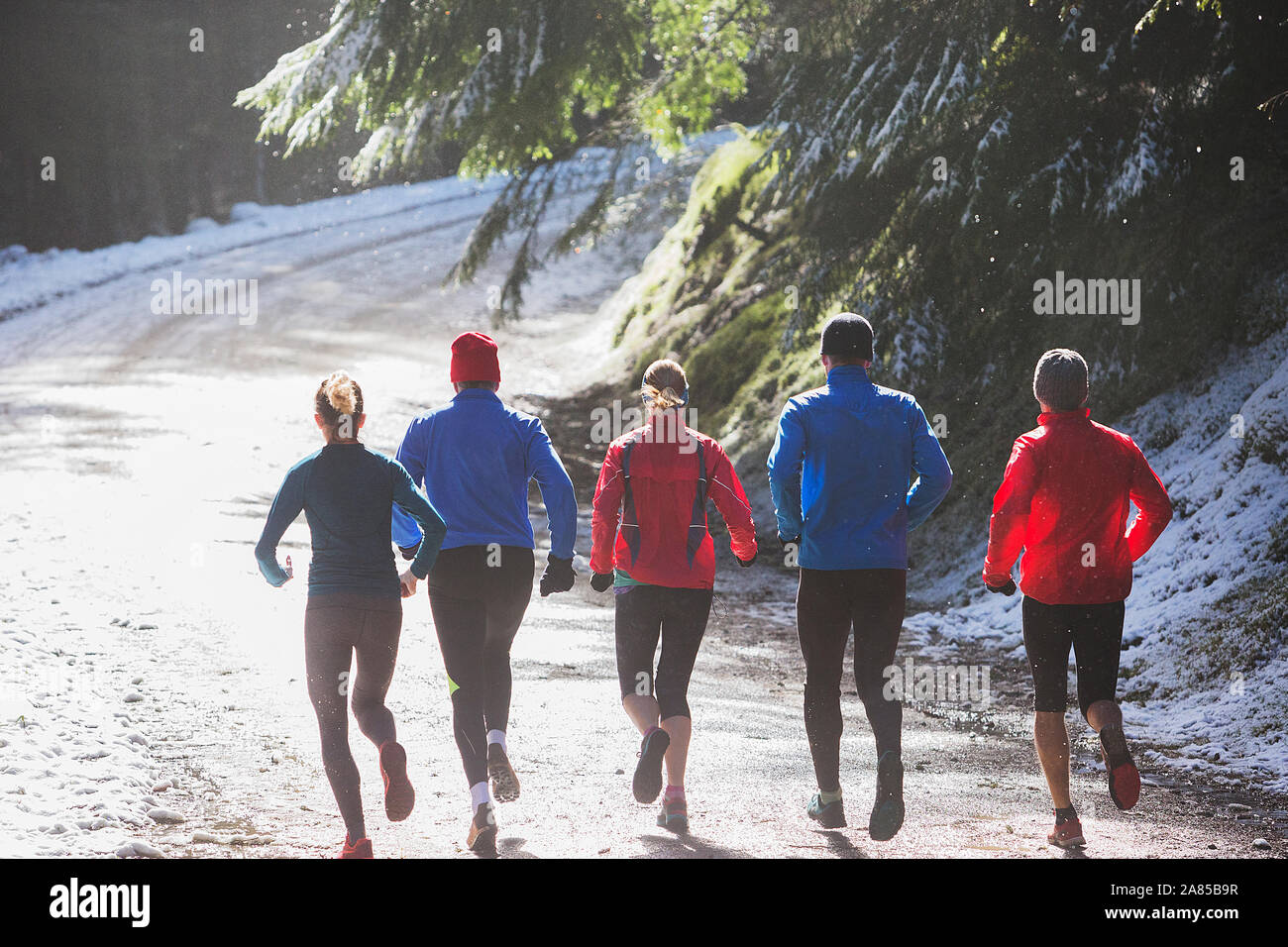 Familie Jogging auf Trail im sonnigen, verschneiten Wald Stockfoto
