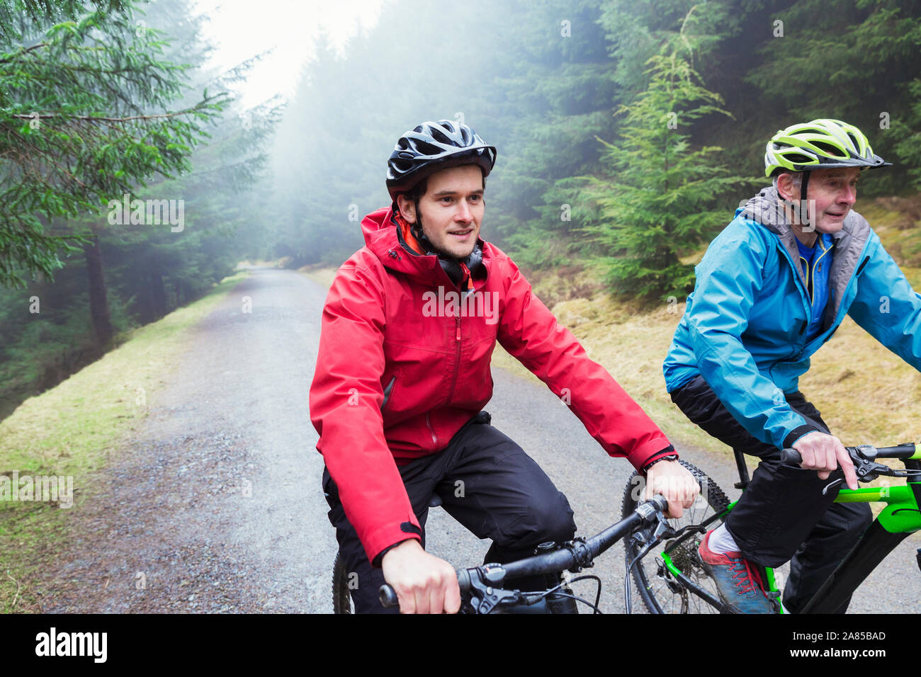 Vater und Sohn Mountainbiken auf Trail im regnerischen Wald Stockfoto