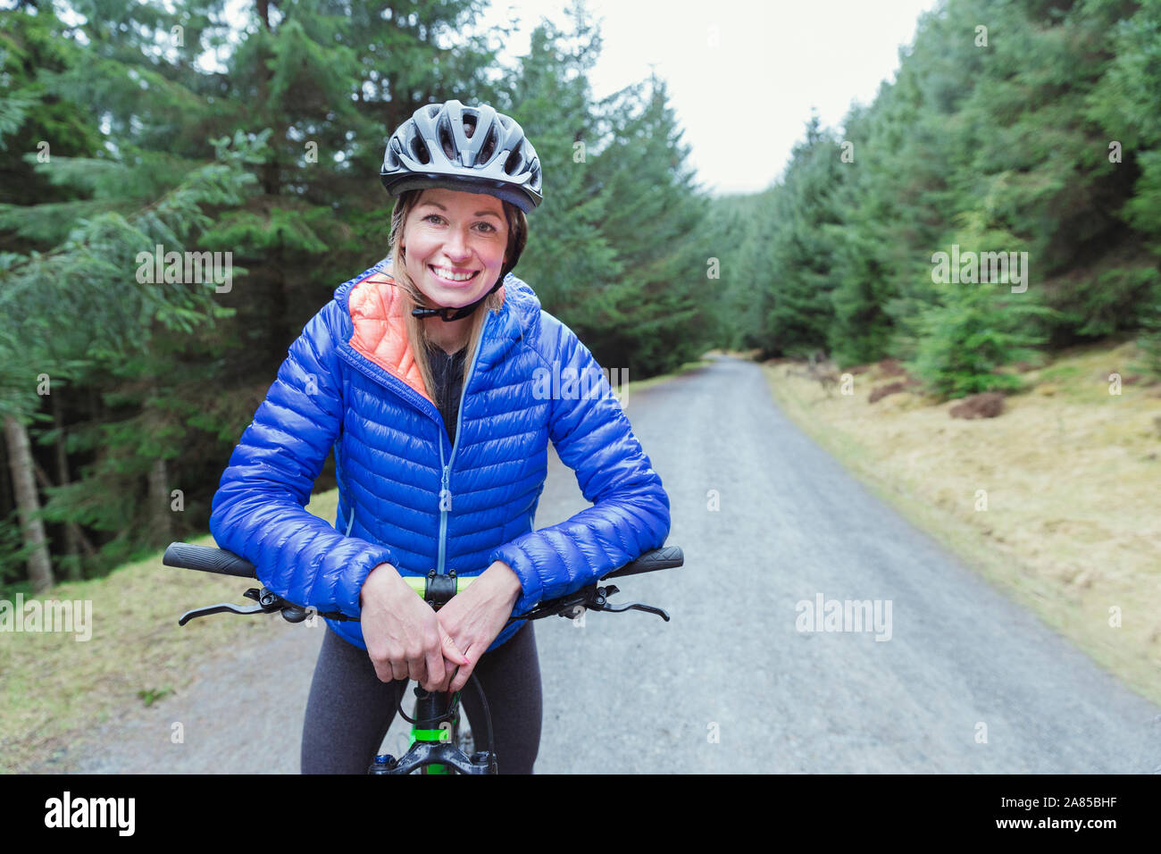 Portrait lächelnde Frau Mountainbiken auf Trail im Wald Stockfoto