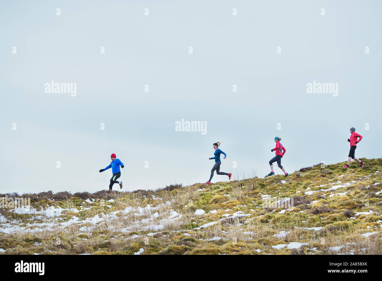 Freunde joggen auf verschneiten Hügel Stockfoto