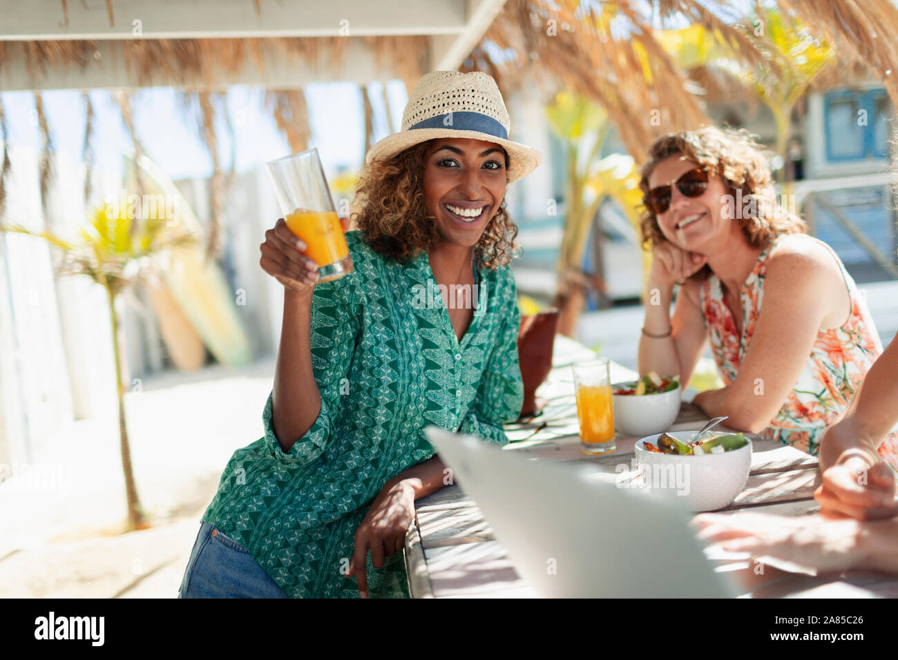 Portrait glücklich Frau trinkt Cocktail an Sunny Beach Bar Stockfoto