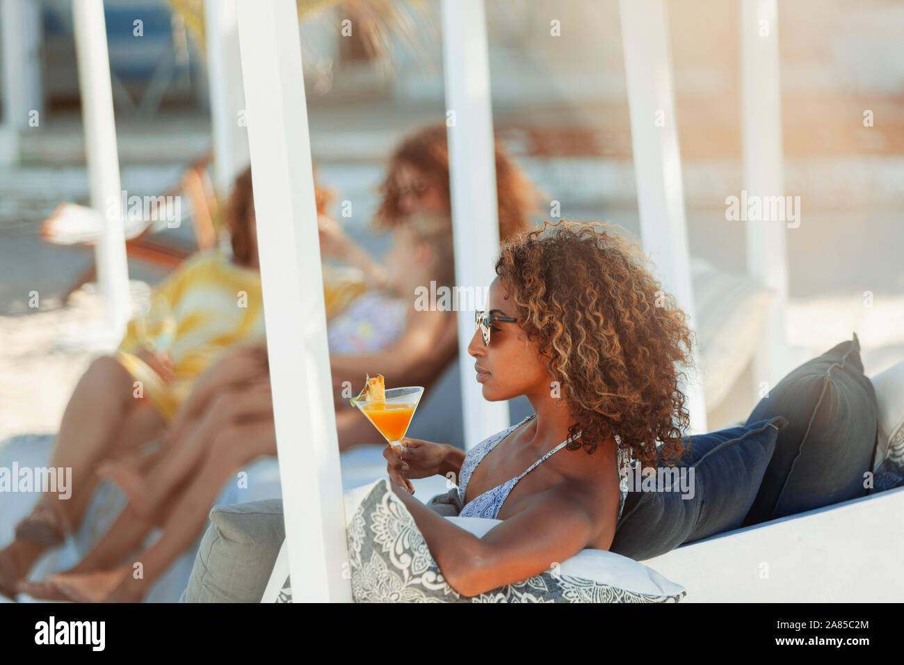 Junge Frau mit Cocktail am Strand Terrasse Stockfoto