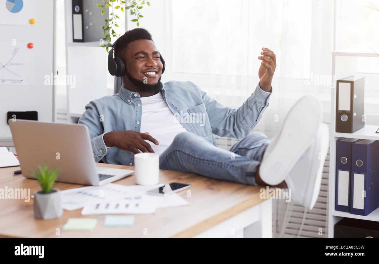 Schwarze Arbeiter hören Musik in Büro und Spielen von virtuellen Gitarre Stockfoto