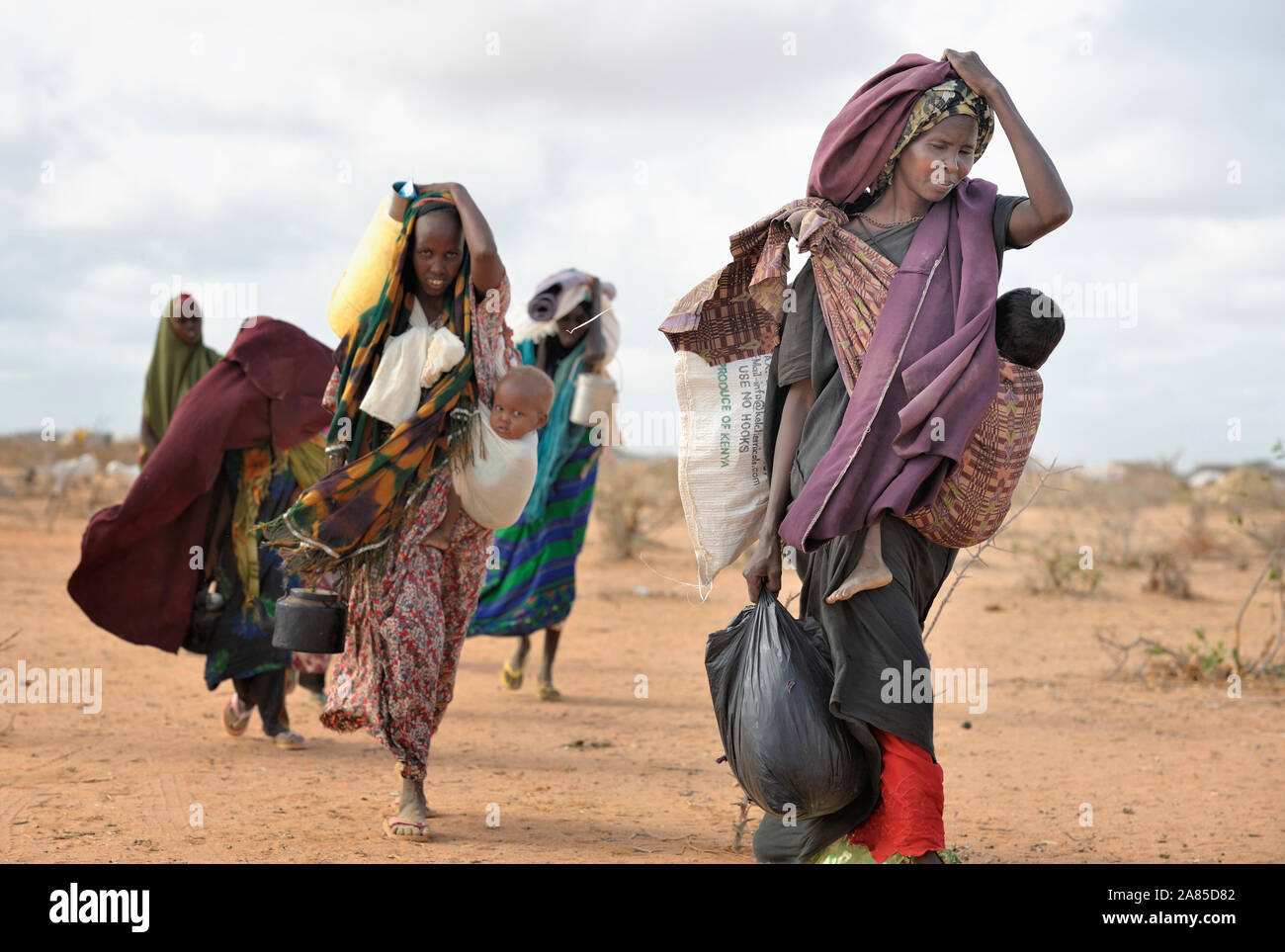 Eine Mutter und ihre Kinder - neu Flüchtlinge angekommen - tragen ihre Habseligkeiten durch das Camp in Dadaab im Nordosten Kenias. Stockfoto