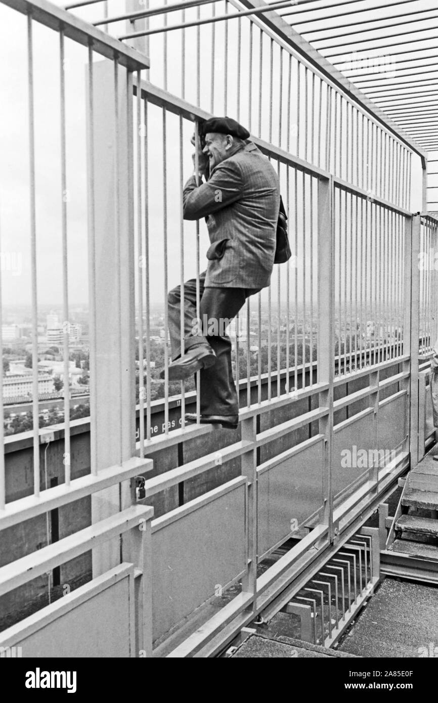 Der Fotograf Erich Andres sucht sich in einem Absperrgitter und Beispiele hängend, den Blick für sein Foto von Berlin, Deutschland 1984. Fotograf Erich Andres hängen in einem Schutzgitter die beste Ansicht für sein Foto, Berlin, Deutschland 1984 zu finden. Stockfoto