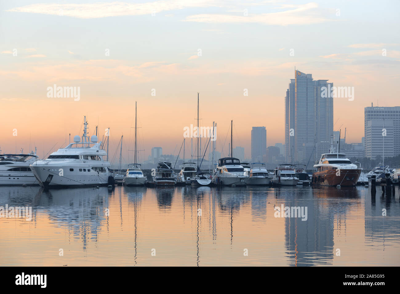 Manila, Philippinen - 26. Juni 2017: Sonnenuntergangs-Meereslandschaft der Bucht von Manila, die das Meer und die große Stadt dahinter reflektiert Stockfoto