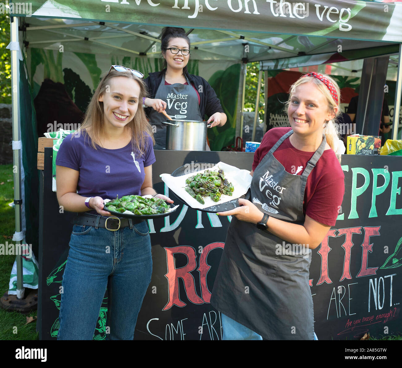Organische Inhaber locken Besucher nach Abergavenny Food Festival stall Russisch Roulette mit padron Paprika, Wales, Großbritannien Stockfoto