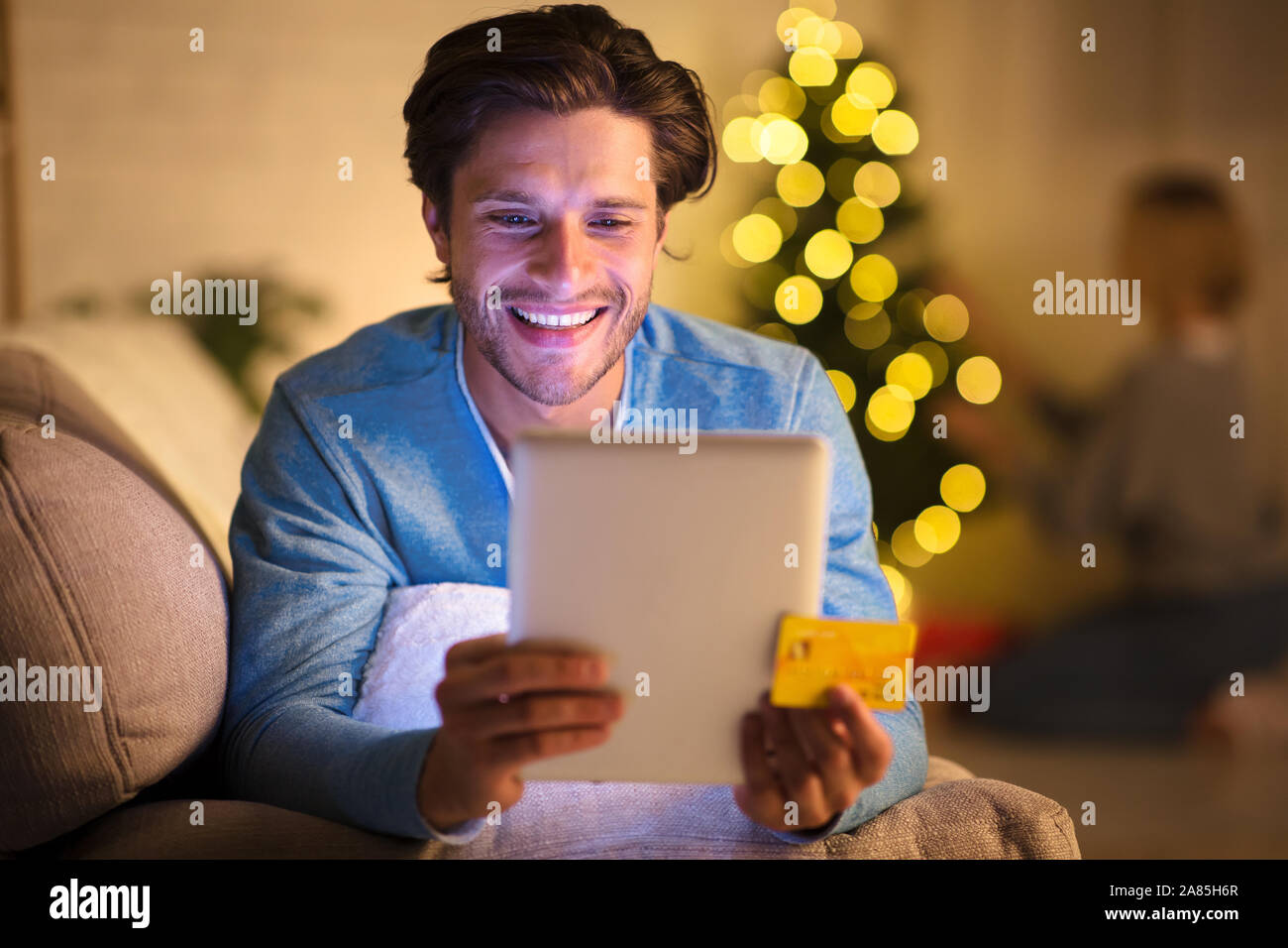 Lächelnd Kerl bestellen Weihnachtsgeschenke auf Tablet Stockfoto