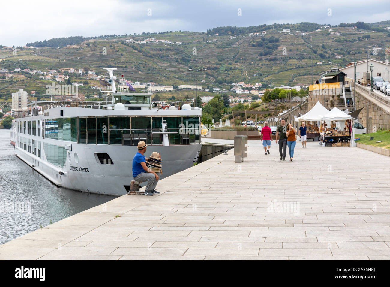 Ein Hut Verkäufer wartet unter einem bewölkten Himmel für Touristen aussteigen aus Ihrer Kreuzfahrt auf dem Fluss Douro in Peso de Requa Stockfoto