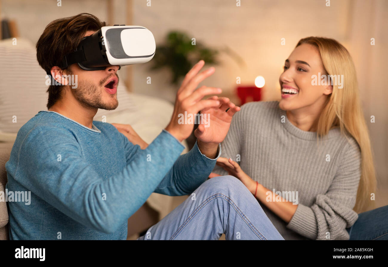 Freund und Freundin mit VR-Headset sitzen auf dem Boden Innen Stockfoto