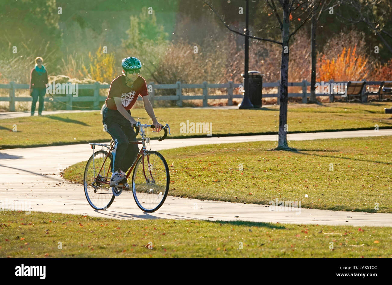 Ein älterer Fahrrad Fahrer navigiert einen gepflasterten Weg entlang des Deschutes River im Farewell Bend Park, in Bend, Oregon. Stockfoto