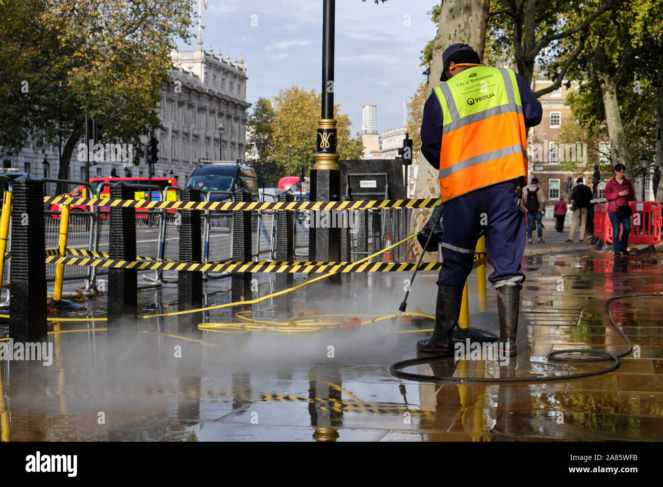 Stadt von Westminster Arbeiter Reinigung Gehweg mit starken Wasserstrahl Reiniger Stockfoto