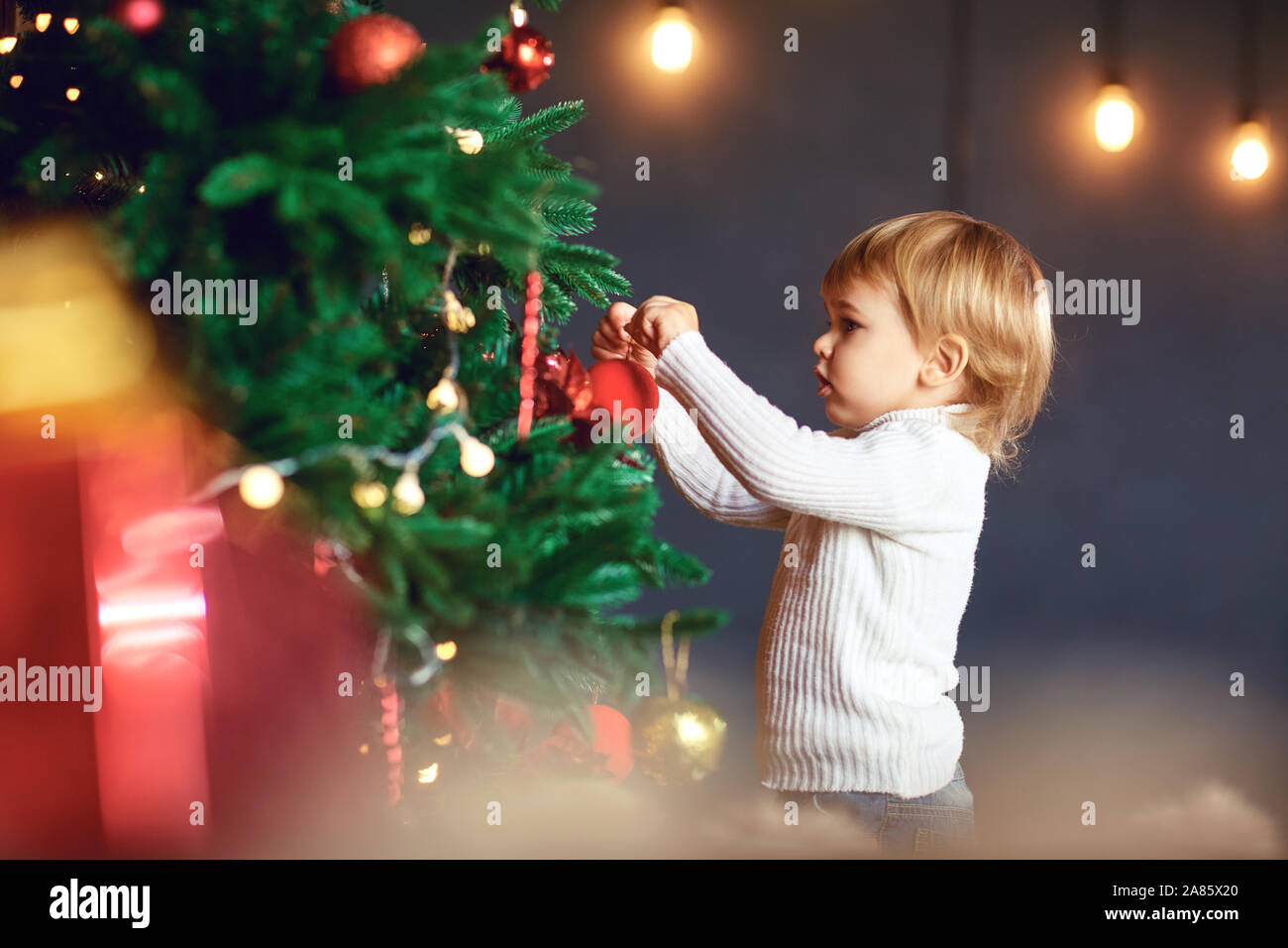 Ein kleiner Junge schmückt den Weihnachtsbaum Stockfoto