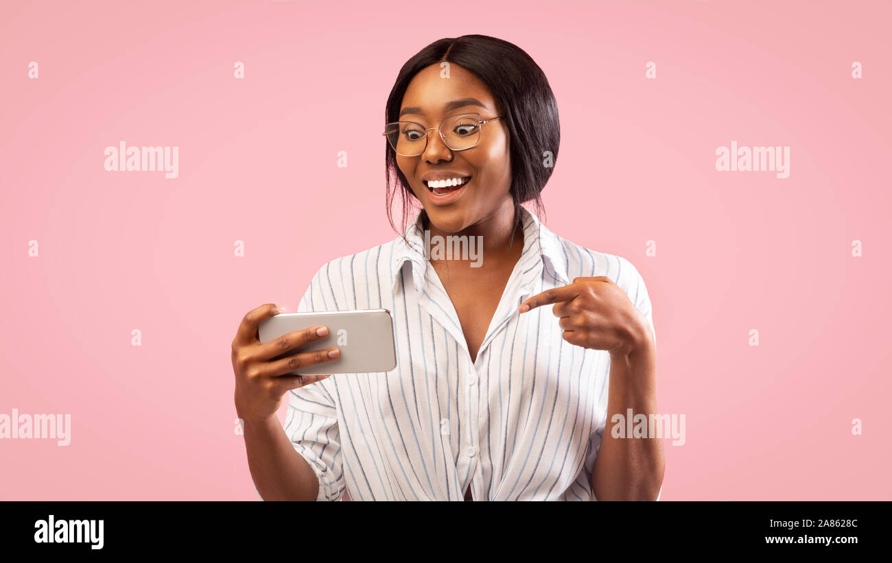 Afro Girl Holding Cellphone lächelnd auf rosa Hintergrund, Panorama Stockfoto