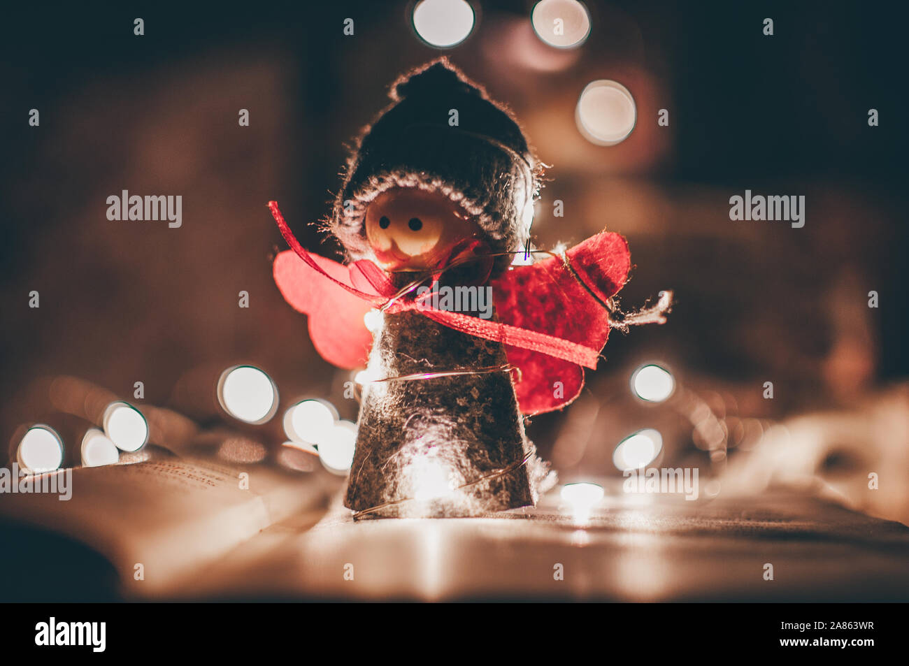 Holz Engel Weihnachten Girlande steht auf einem Buch, im Hintergrund ist eine LED-Kranz. Weihnachten Konzept. Stockfoto