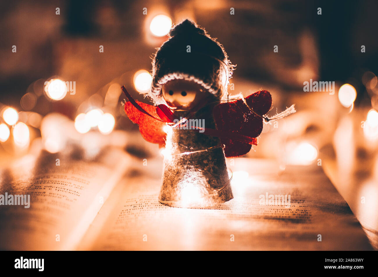 Holz Engel Weihnachten Girlande steht auf einem Buch, im Hintergrund ist eine LED-Kranz. Weihnachten Konzept. Stockfoto