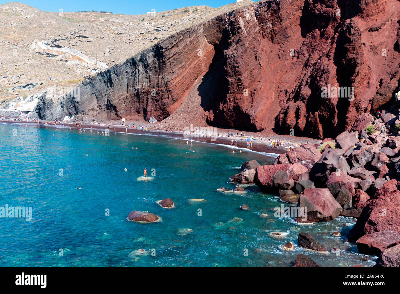 Touristen, Sonnenbaden und Schwimmen am Roten Strand auf der Insel Santorin in Griechenland. Stockfoto