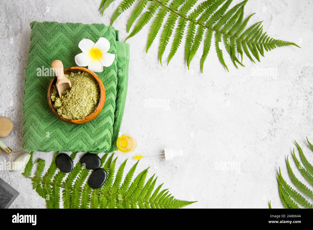 Spa noch Leben mit grünen Blättern, Grüner lehm Pulver zur Herstellung einer Gesichtsmaske, Handtuch, Massage Steine, frangipani Blume und Ölflasche, Ansicht von oben Stockfoto