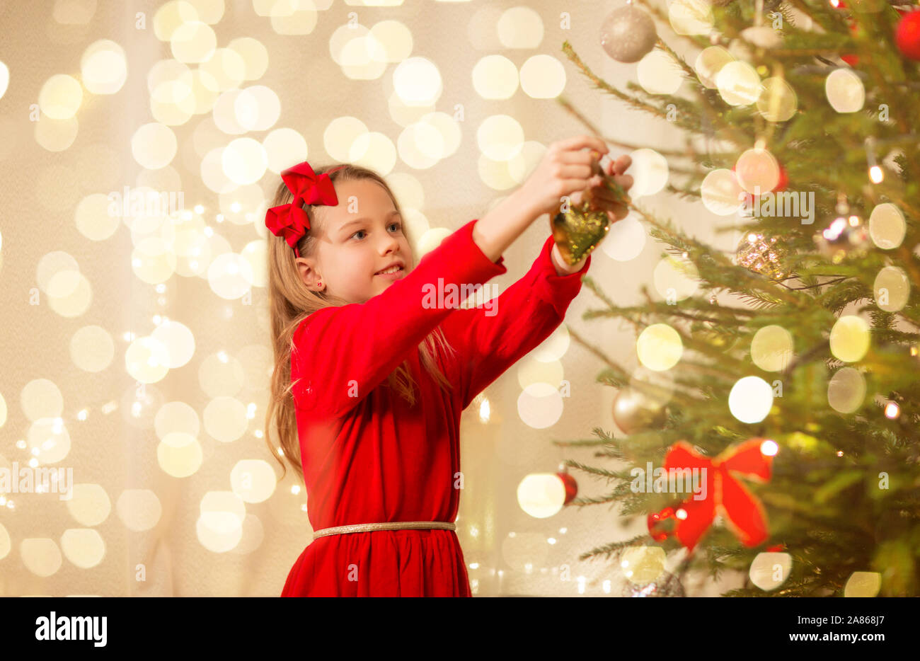 Glückliches Mädchen im roten Kleid Dekoration Weihnachtsbaum Stockfoto