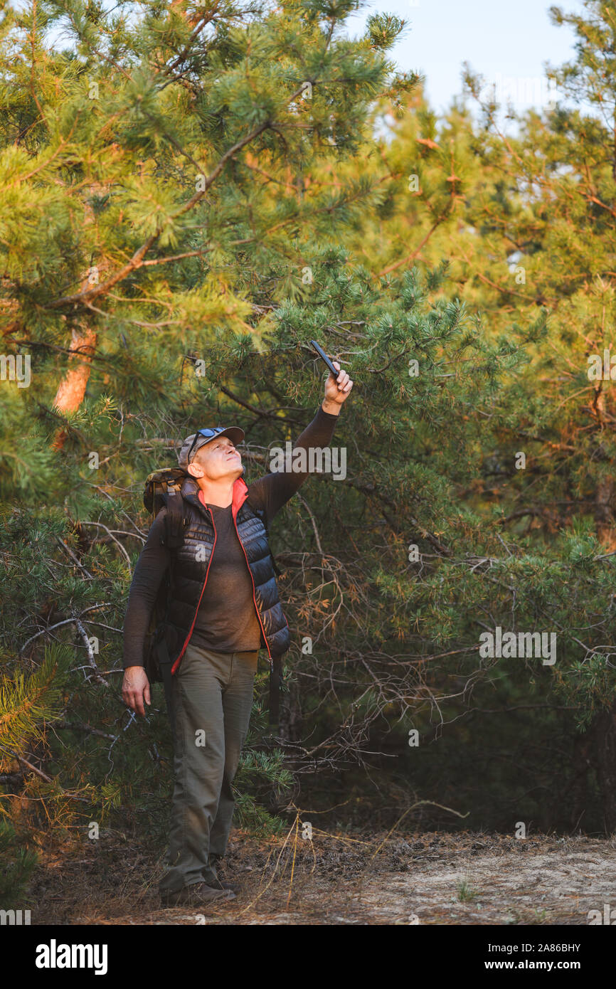 Wanderer auf der Suche nach seinem GPS-Signal auf einem Smartphone, in üppigen Wäldern desorientiert, die versuchen, einen Ausweg zu finden. Der Mensch mit seiner mobilen Smart Phone Suche f Stockfoto