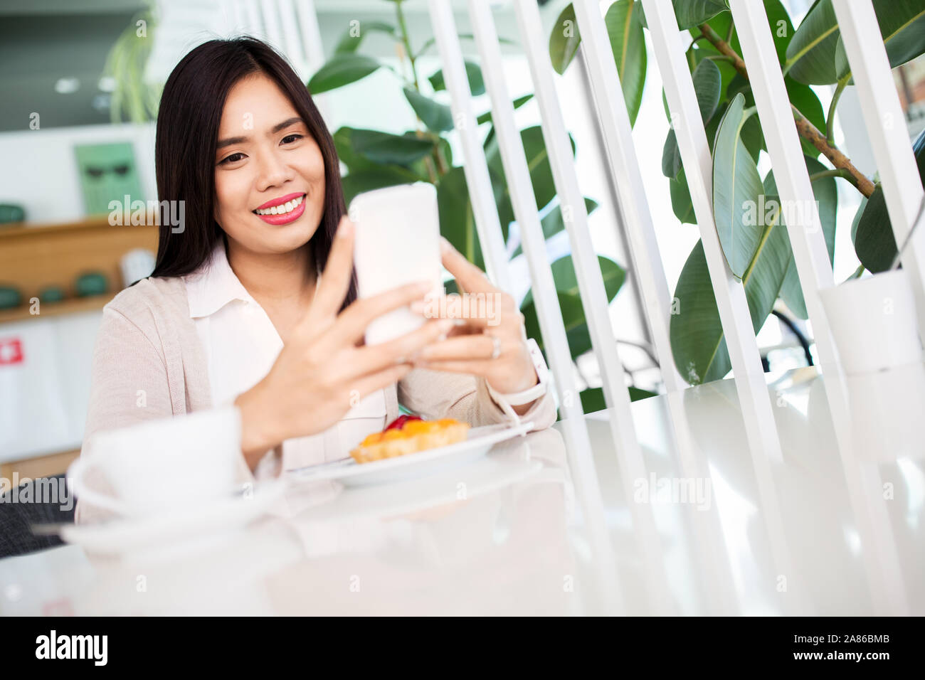 Asiatische Frau mit Smartphone im Cafe oder Tee Shop Stockfoto