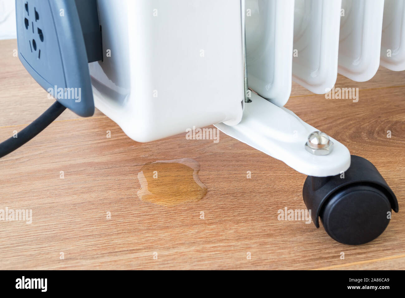 Öl tropft auf den Boden von einer beschädigten Ölheizung. Fehlfunktion der elektrischen Home kühler und Reparatur von Haushaltsgeräten. Vorderansicht. Stockfoto