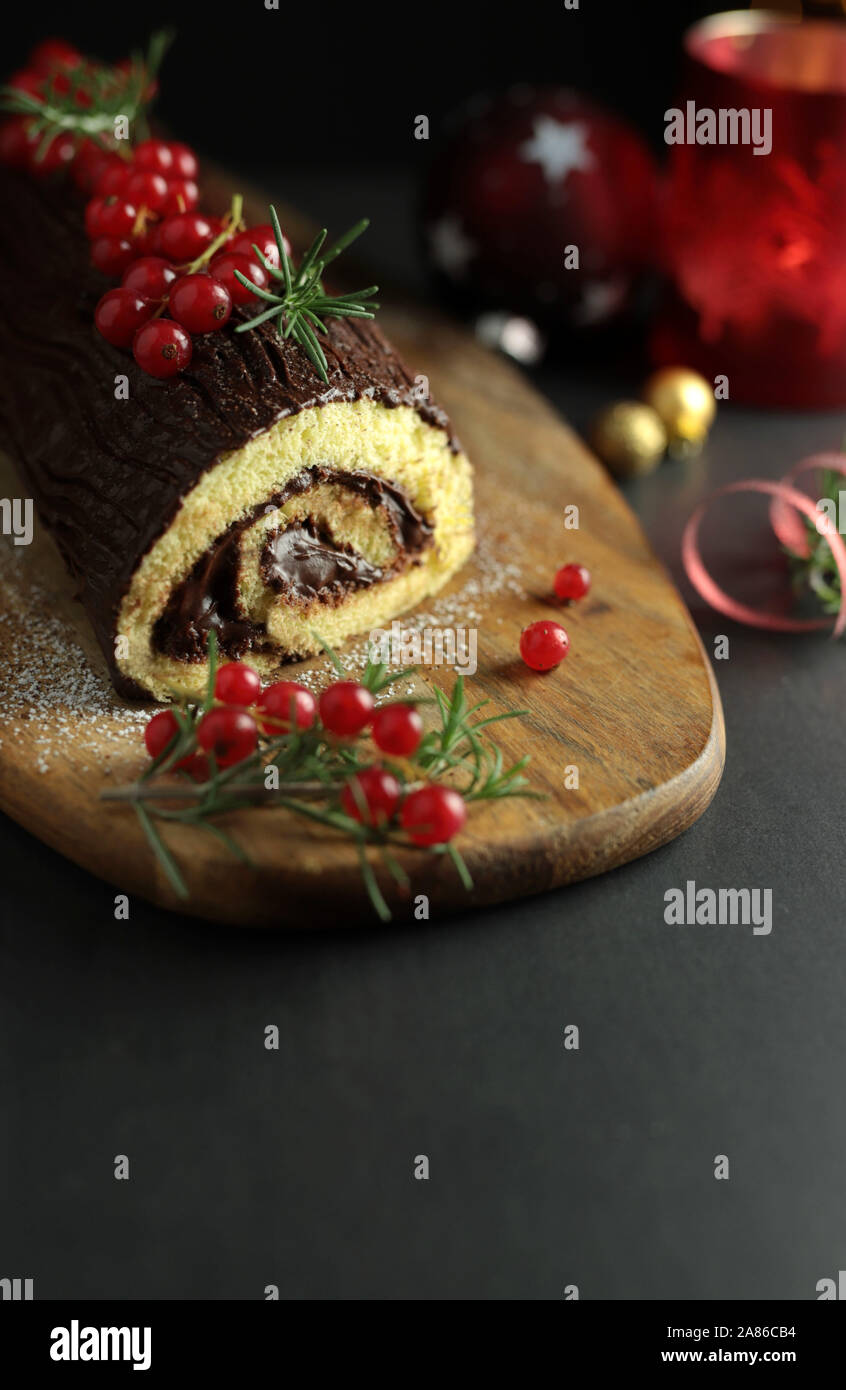 Schokolade Weihnachten Yule Log, Buche de Noel auf Holz Schneidebrett. Weihnachten Dekoration auf dunklem Hintergrund. Nahaufnahme Stockfoto