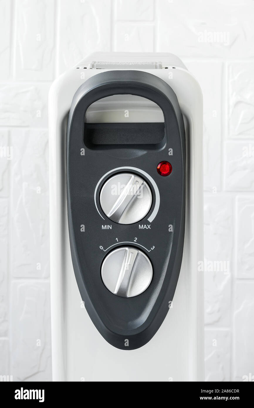 Strom- und Thermostat Knöpfe und die rote Leuchte auf der Vorderseite eines elektrischen Ölheizung. Weiß-Öl-gefüllte Kühler für Heim und Büro. Stockfoto