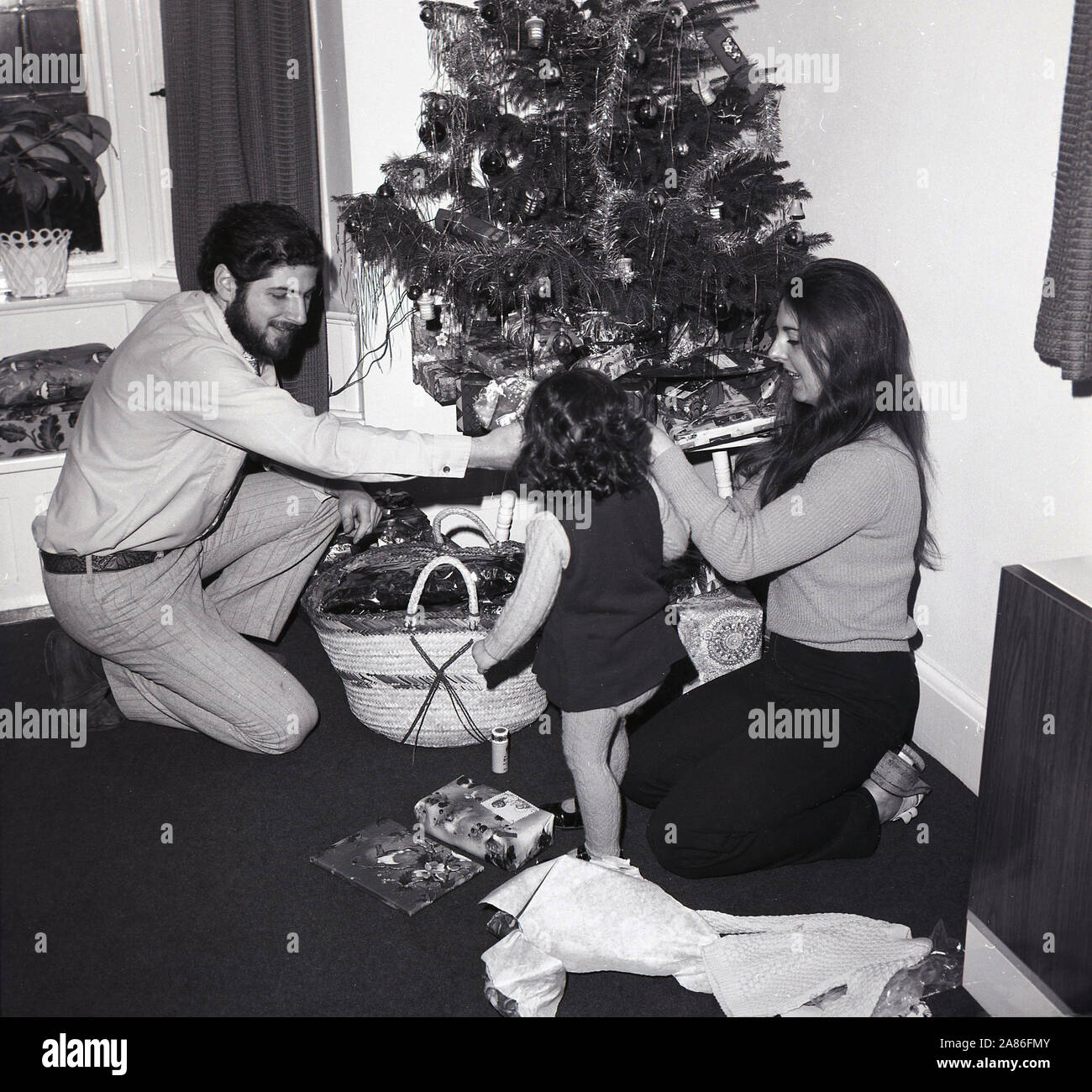 1970er Jahre, historisch, Weihnachten, England, Großbritannien. Eröffnungsgeschenke, Mutter und Vater mit kleiner Tochter. Stockfoto